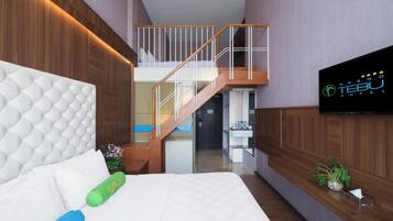 A modern hotel room with a large bed, a wooden staircase, a television, and a small plant.