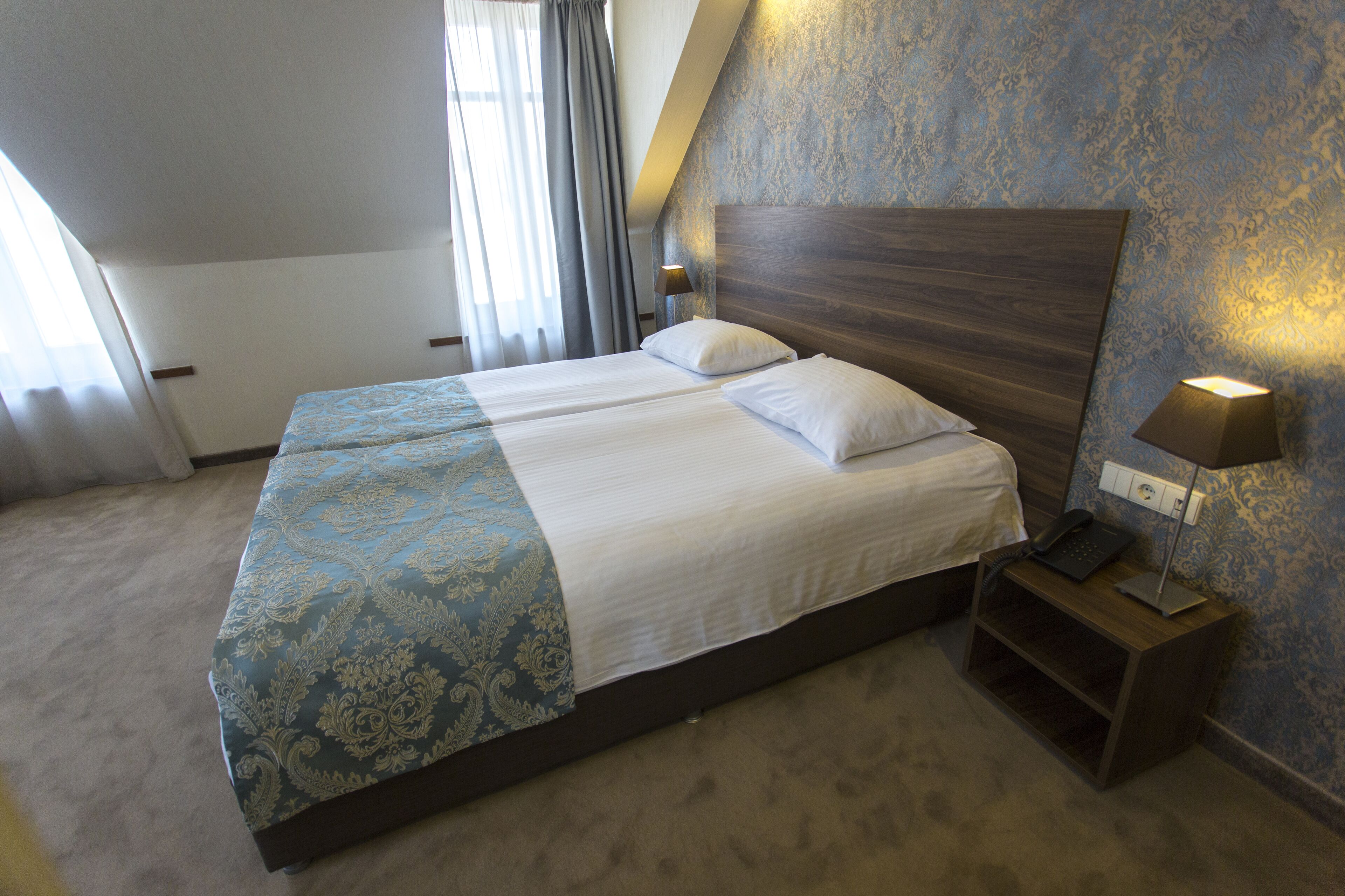 A hotel room with a large bed, two bedside tables, and a nightstand with a lamp.