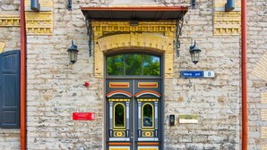 A building facade with a prominent double door, a street sign, and a plaque. - Angleterre Apartments (Tallinn)