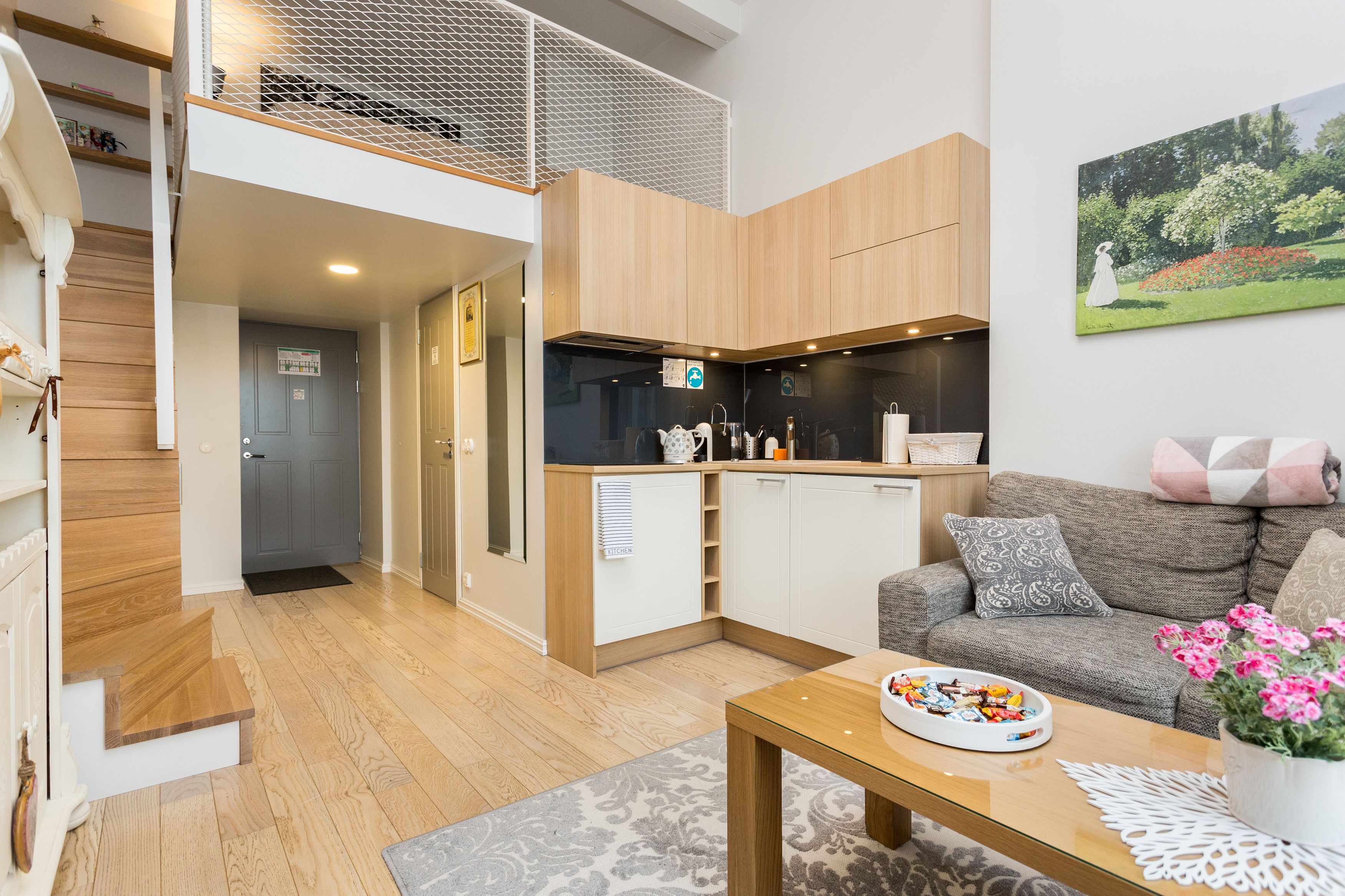 A modern apartment with a kitchen, living area, and a staircase leading to an upper level.