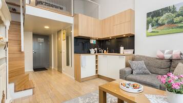 A modern apartment with a kitchen, living area, and a staircase leading to an upper level.