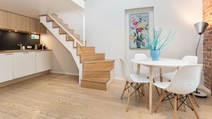 A modern kitchen with wooden cabinets and a staircase leading to an upper level. - Angleterre Apartments (Tallinn)