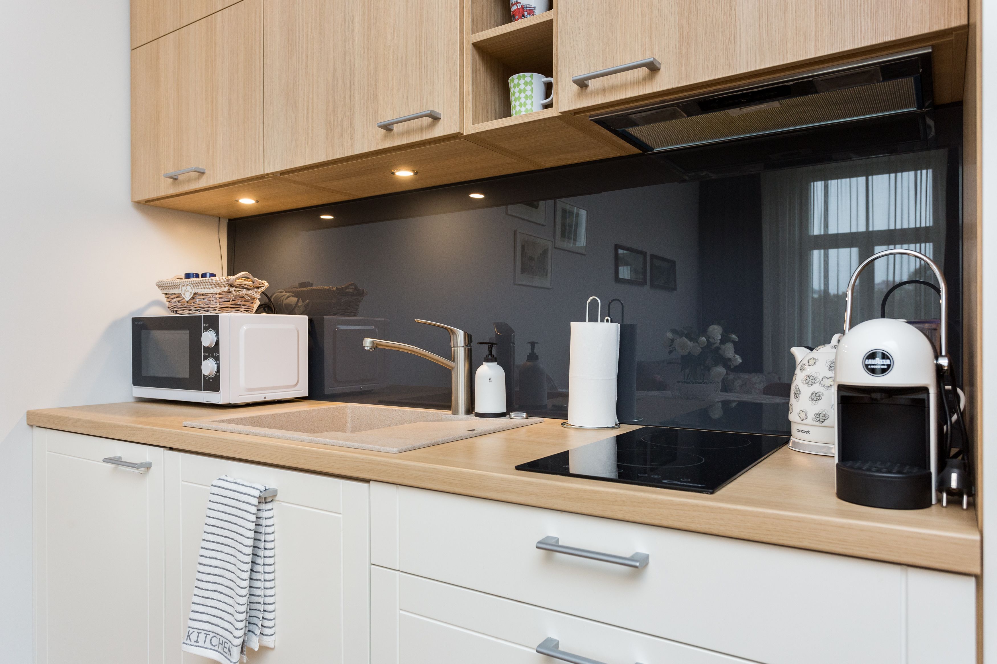 A modern kitchen with a microwave, kettle, and coffee maker on the counter.