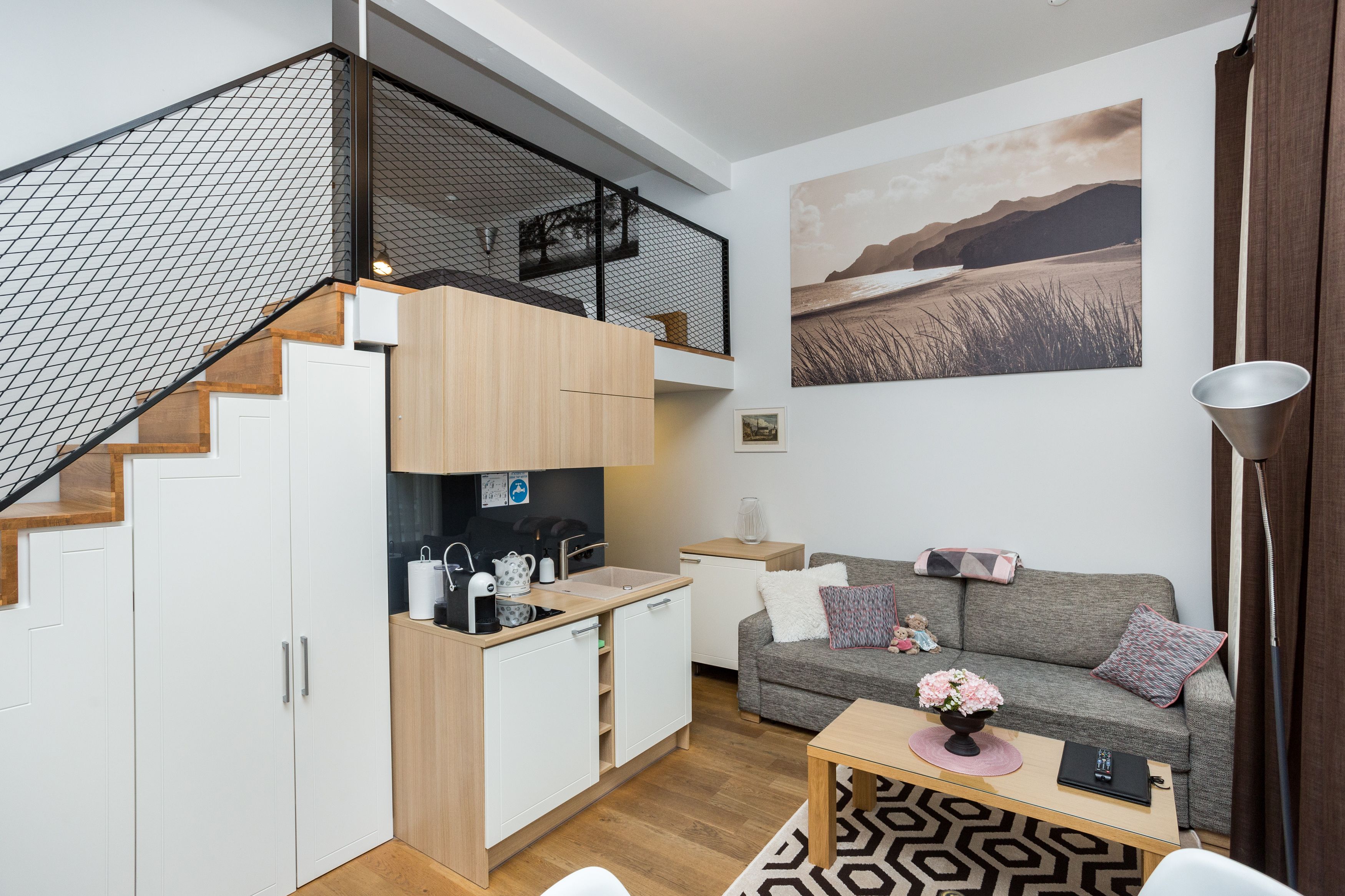 A compact living space with a kitchen, a sofa, and a staircase.