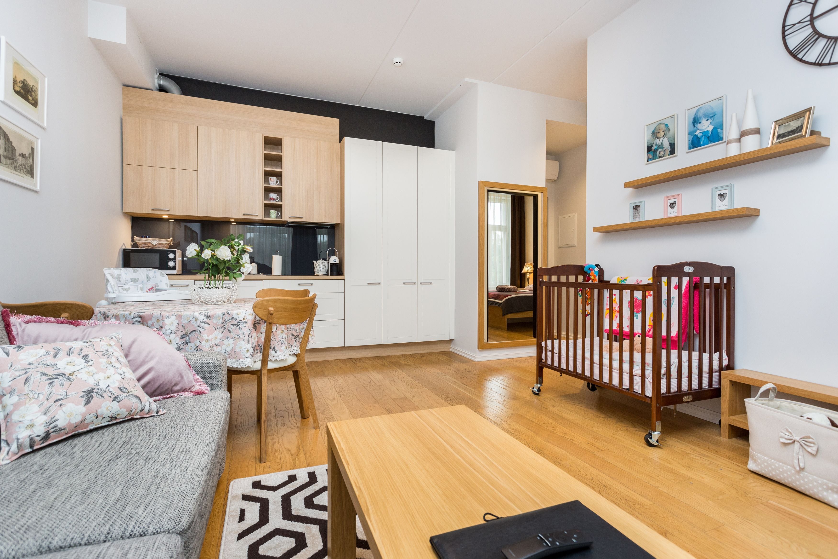 A modern living room with a sofa, a wooden table, and a crib.