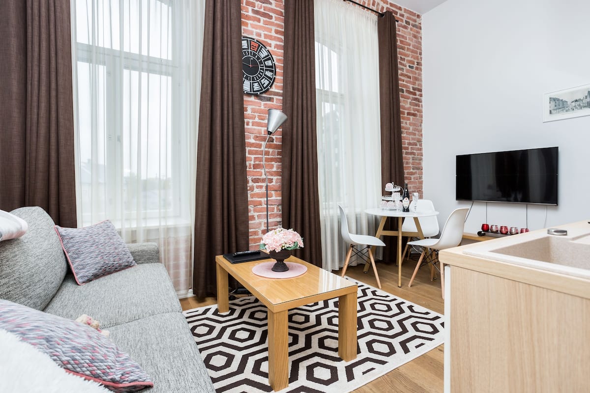 Ein modernes Wohnzimmer mit einer Couch, einem Couchtisch, einem Fernseher und einem Essbereich mit Stühlen.
