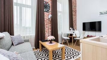 Een moderne woonkamer met een bank, een salontafel, een televisie en een eethoek met stoelen.