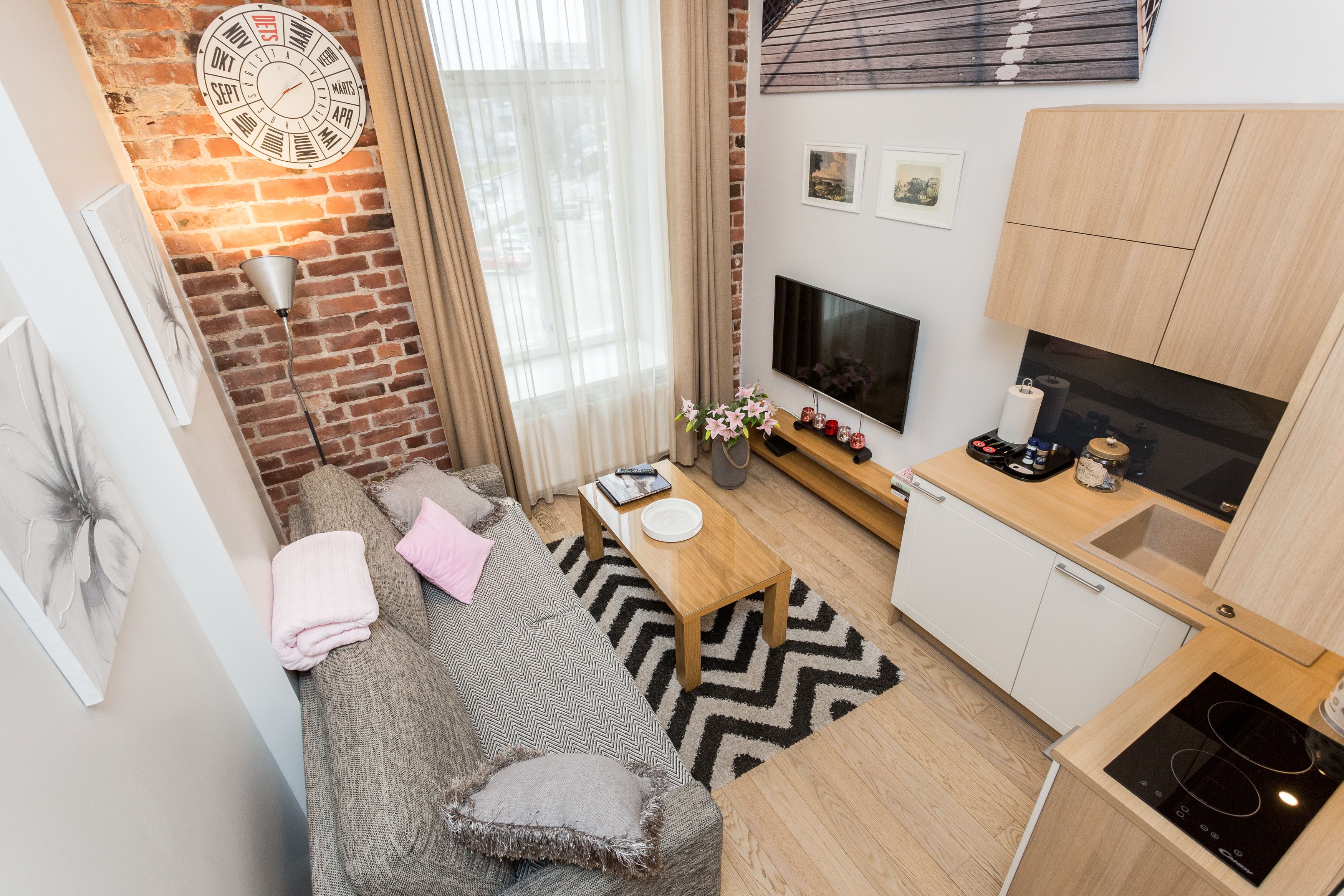 Ein kompakter Wohnbereich mit Sofa, kleinem Tisch, Fernseher und Küchenzeile.