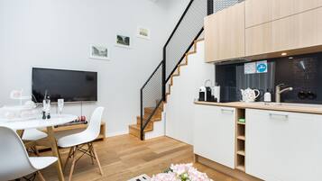Una cucina moderna con mobili bianchi, una scala in legno e un televisore a schermo piatto.