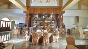 A spacious lobby with a high ceiling, a bar area with a patterned wall, and tables set for dining. - Gracious Bagan Hotel (Nyaung-U)