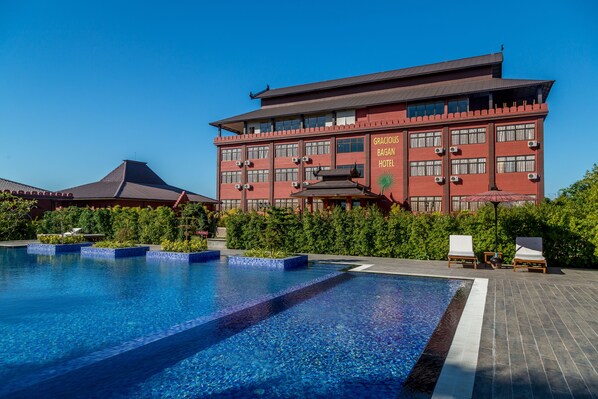 Un hotel con piscina, un edificio grande con varias ventanas y un cielo azul despejado.