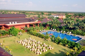Un resort con piscina, mobiliario exterior y abundante vegetación.