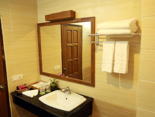 A bathroom with a wooden door, a white sink, and a mirror. There are two towels hanging on a rack.