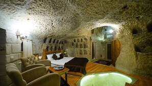 Un interior acogedor y parecido a una cueva, con cama, zona de estar y un elemento decorativo de iluminación central.