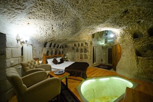 Un interior acogedor y parecido a una cueva, con cama, zona de estar y un elemento decorativo de iluminación central.