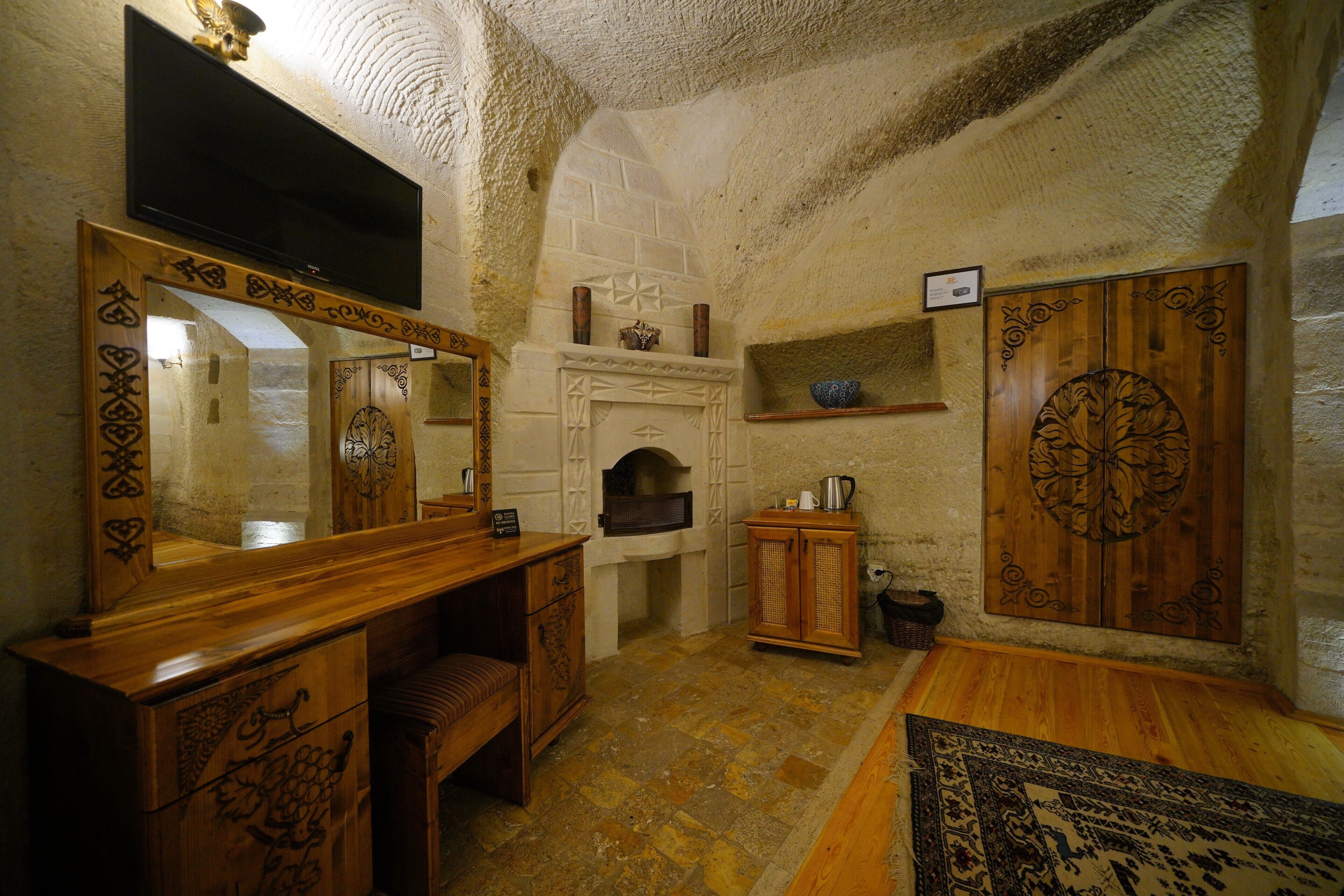 A rustic interior with a stone fireplace, wooden furniture, and a large mirror.