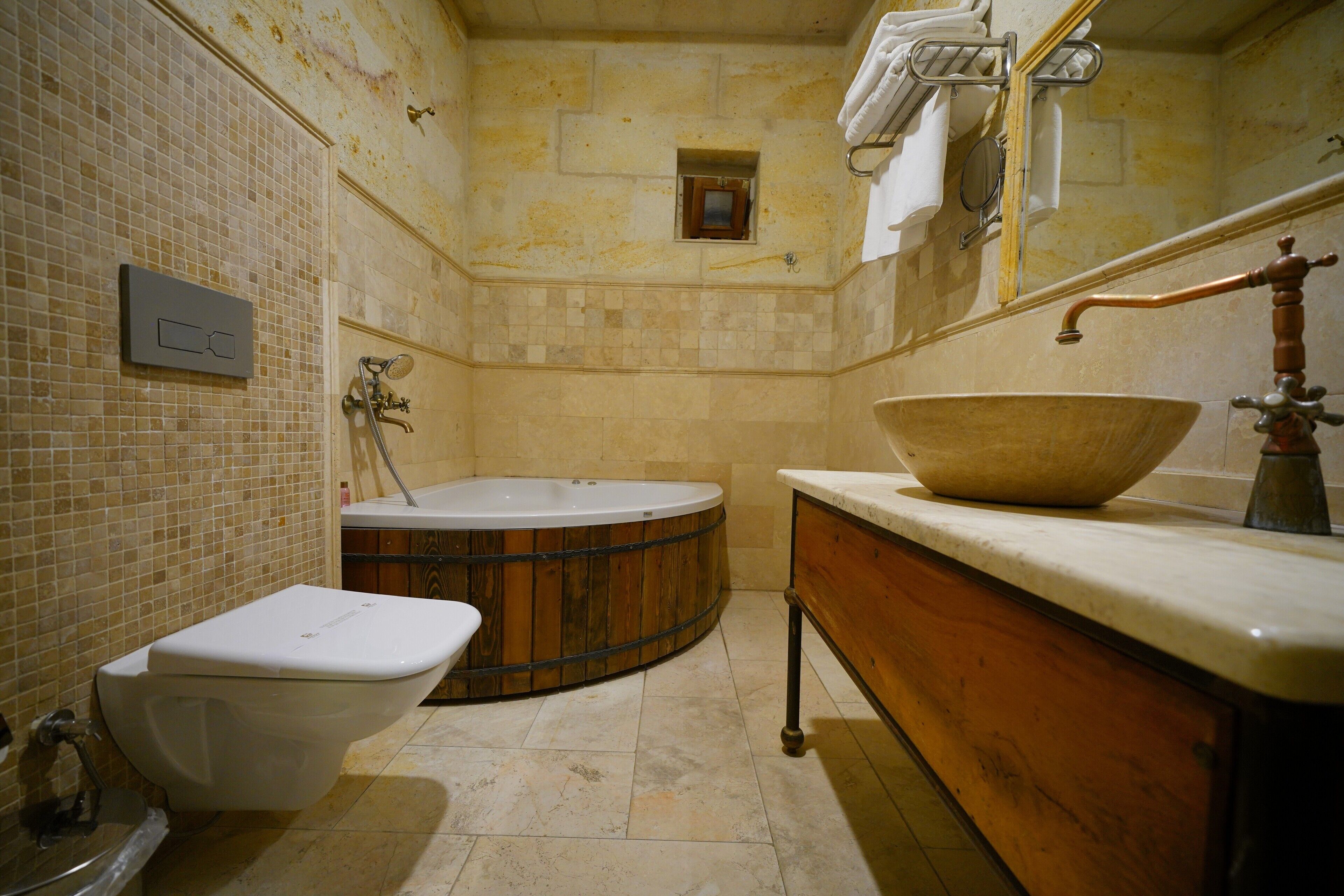 A bathroom with a bathtub, a toilet, and a wooden vanity with a large bowl sink.