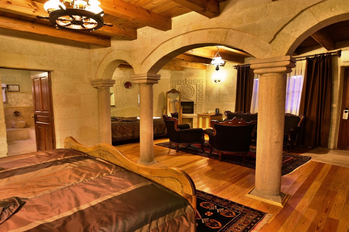 Una habitación con una cama, muebles de madera, una chimenea y paredes de piedra.