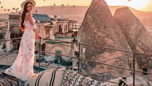 A person standing on a balcony overlooking a mountainous landscape with traditional buildings. - Harman Cave Hotel (Nevsehir)