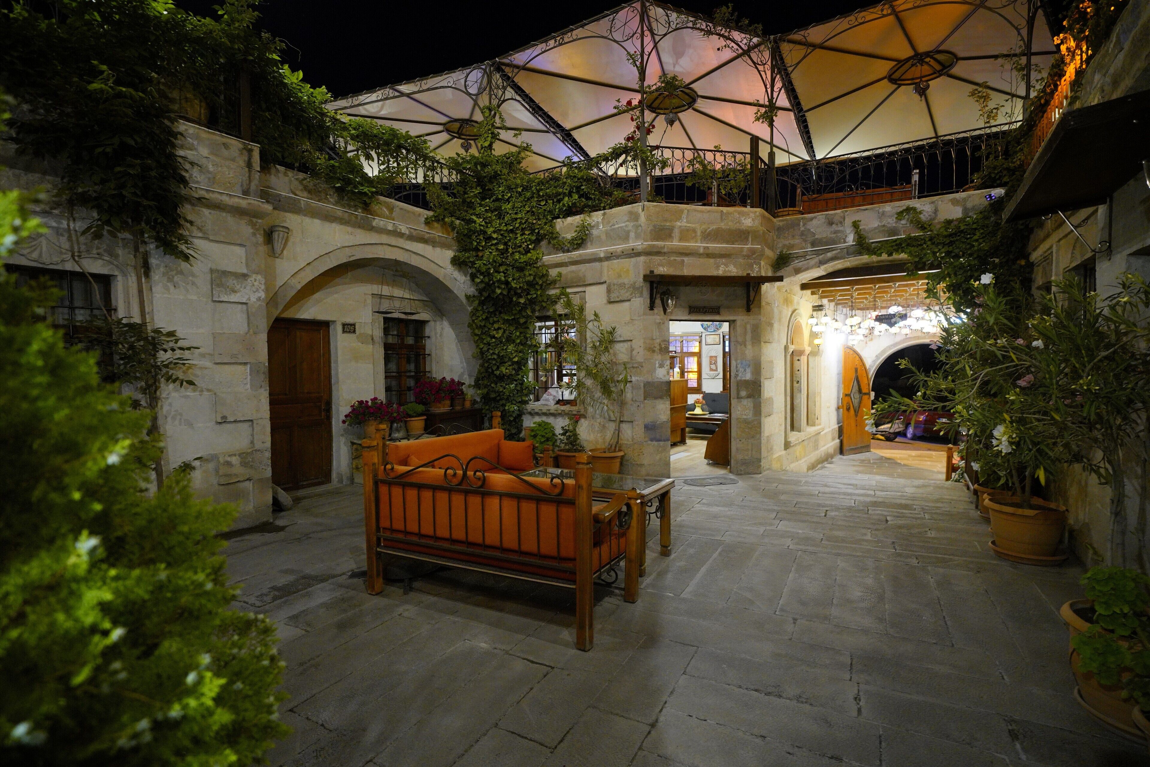 A courtyard with a wooden bench, potted plants, and a large umbrella structure.