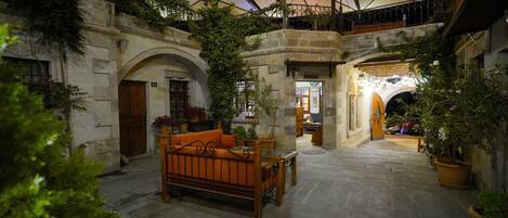 A courtyard with a wooden bench, potted plants, and a large umbrella structure.