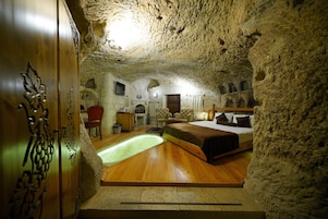 Un dormitorio tipo cueva con una cama, una mesita pequeña y una silla.