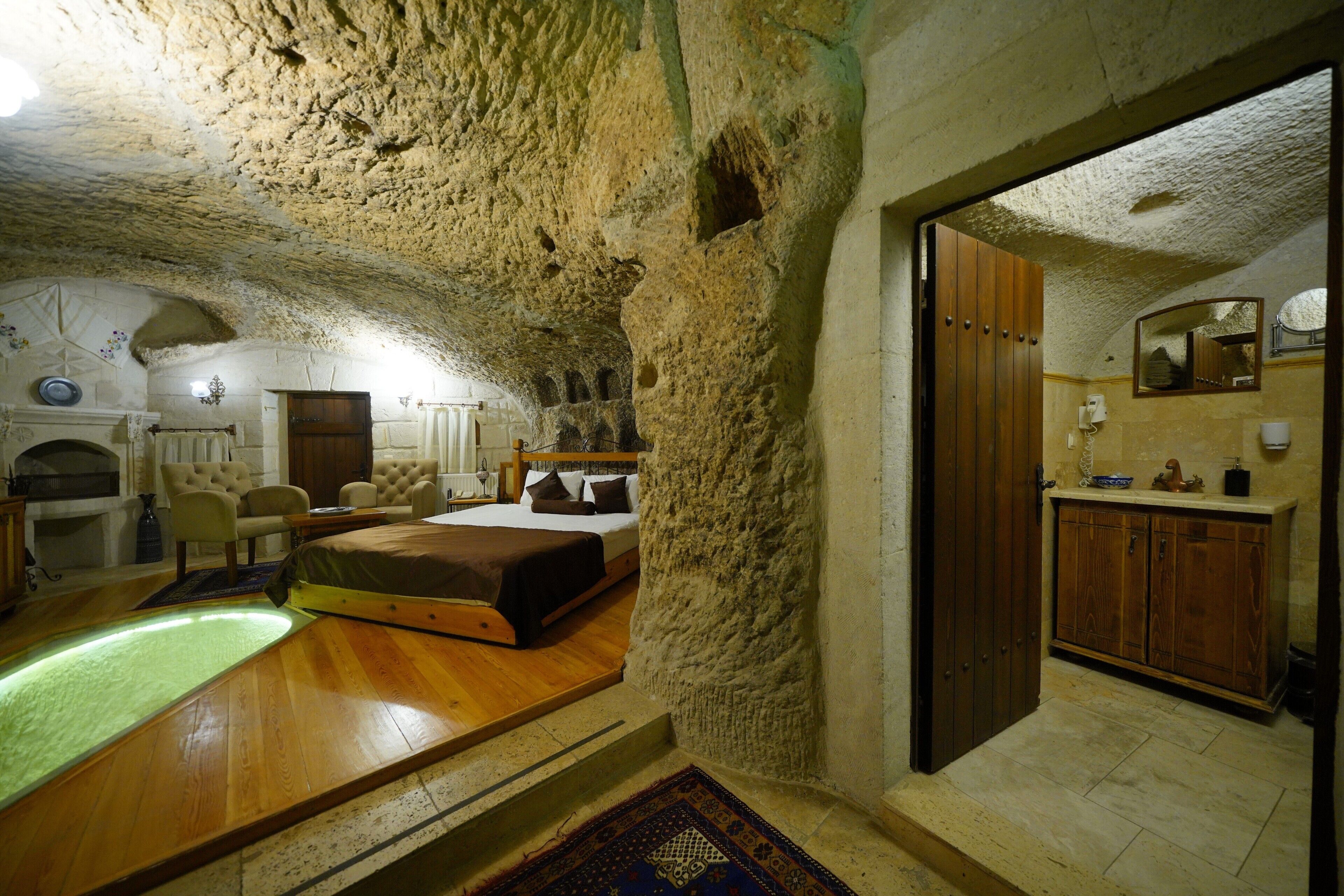 A room with a bed, a wooden table, and a stone wall.
