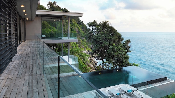 Una casa moderna con una piscina de borde infinito de cristal con vistas al mar.