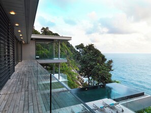 A modern house with a glass infinity pool overlooking the sea.