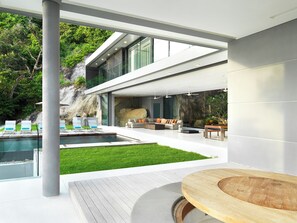 A modern outdoor living area with a pool, seating, and a wooden table.