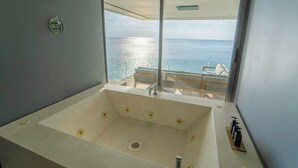 Un baño moderno con una bañera grande, vistas al mar y una zona de estar también con vistas.