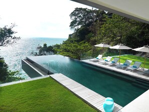 Una piscina al aire libre, sombrillas, sillones reclinables de piscina