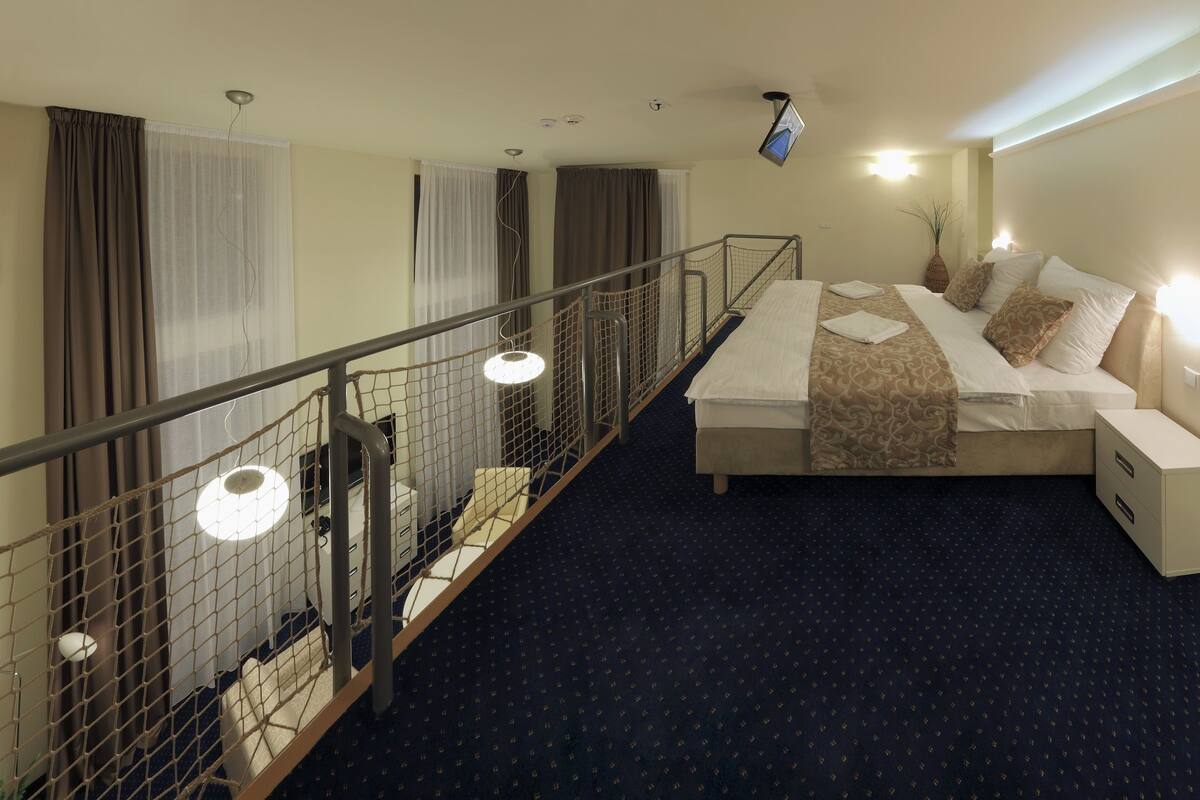 Hotelkamer met een bed, een bureau, een stoel, een tafeltje, een lamp, een televisie, een raam en een balkon.