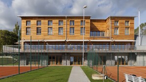 Un bâtiment moderne à plusieurs étages, doté de grandes fenêtres et d’un espace extérieur abrité.