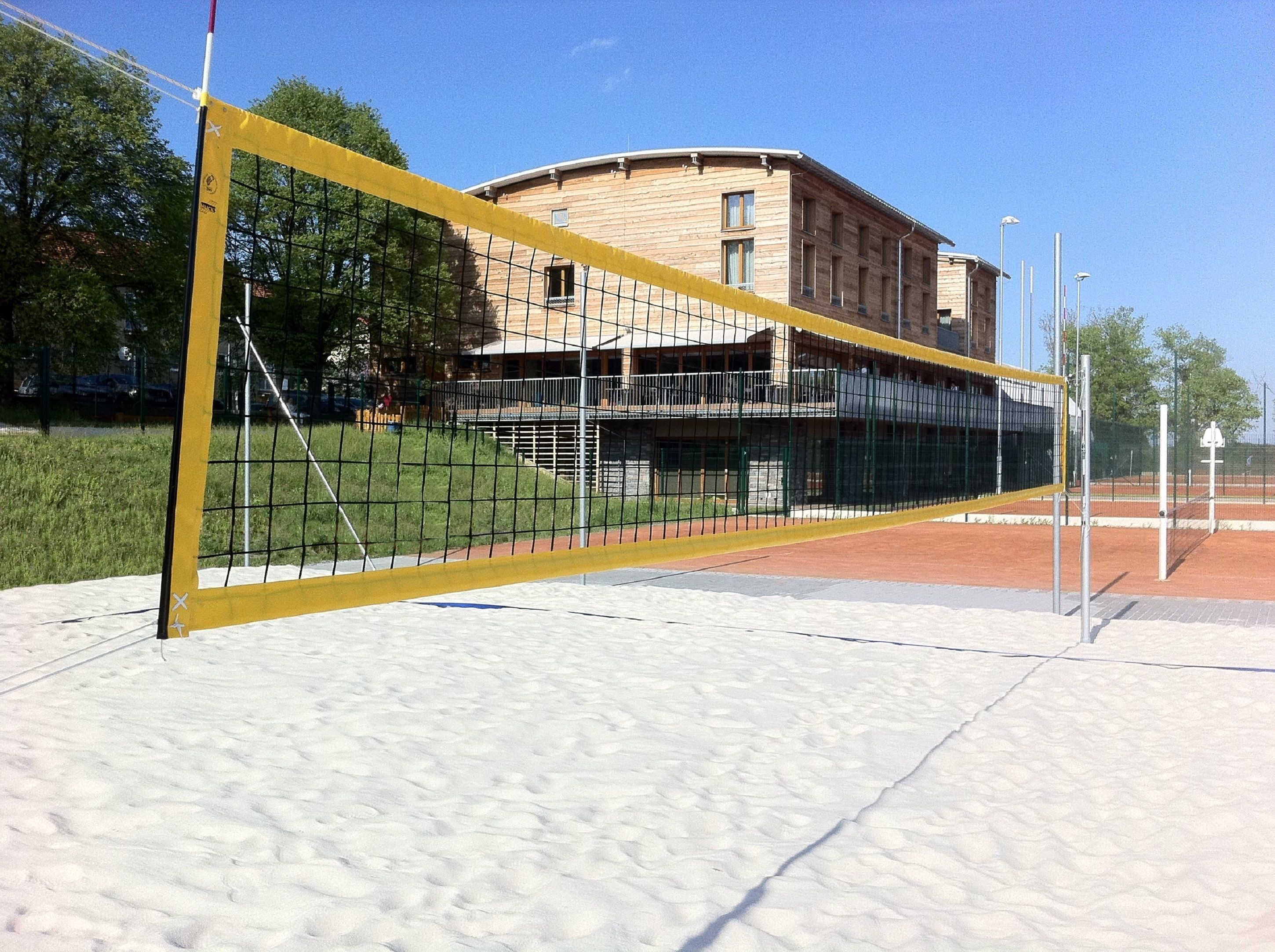 Un filet de volley-ball sur un terrain sablonneux, avec un bâtiment en arrière-plan.