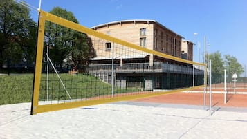 Un filet de volley-ball sur un terrain sablonneux, avec un bâtiment en arrière-plan.