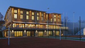 Un immeuble à plusieurs étages doté d’un balcon et d’un court de tennis à l’avant.