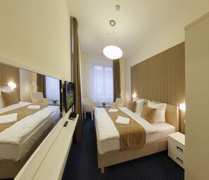 Une chambre d’hôtel avec deux lits, une télévision, un bureau et un miroir.
