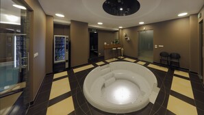 Un hall d’hôtel moderne doté d’un grand jacuzzi central, d’un distributeur automatique et d’un espace détente avec des fauteuils.