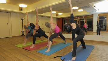 A yoga class in a room with wooden floors and mirrored walls.