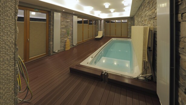 Un espace bien-être comprenant un jacuzzi, un plancher en bois, des murs en pierre et des portes coulissantes.