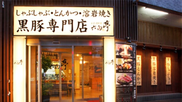 A restaurant with a sign in Japanese, a glass door entrance, and a small outdoor seating area.
