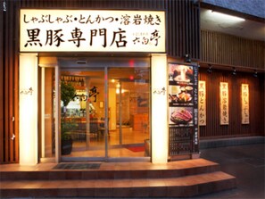 A restaurant with a sign in Japanese, a glass door entrance, and a small outdoor seating area.