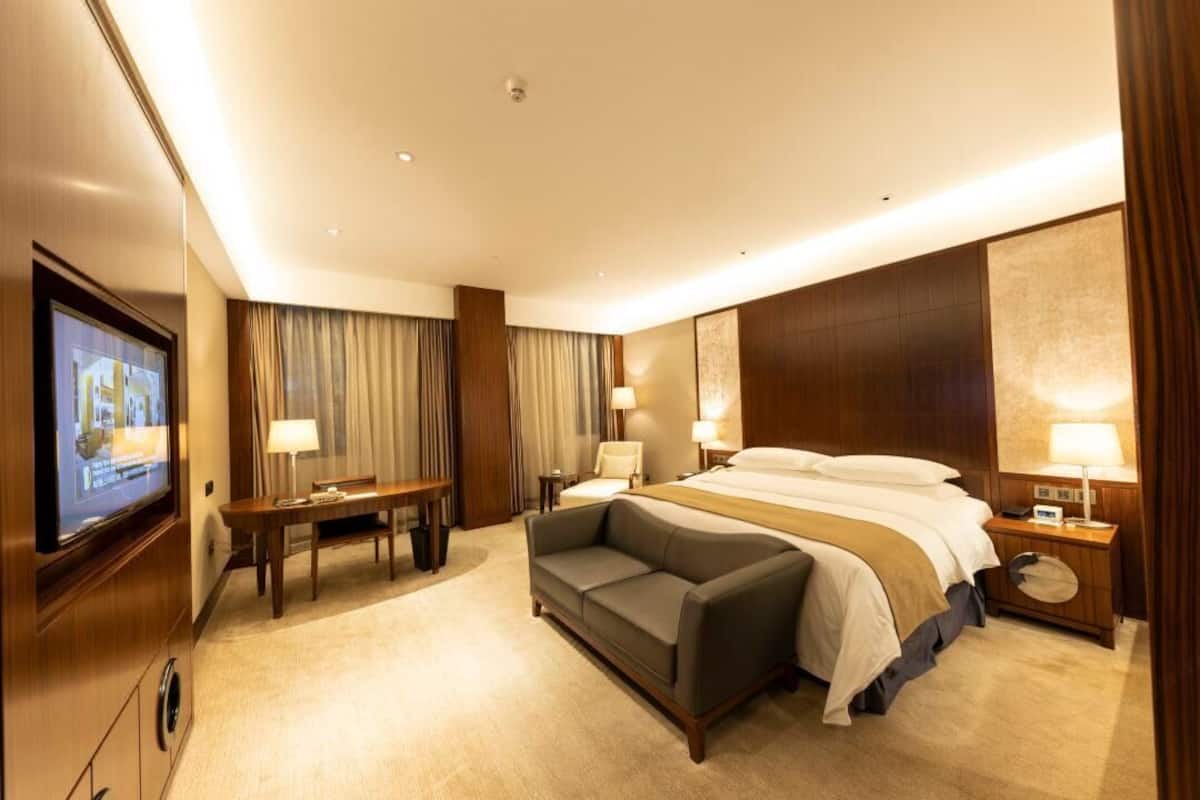 A hotel room with a bed, a sofa, a TV, and a desk.