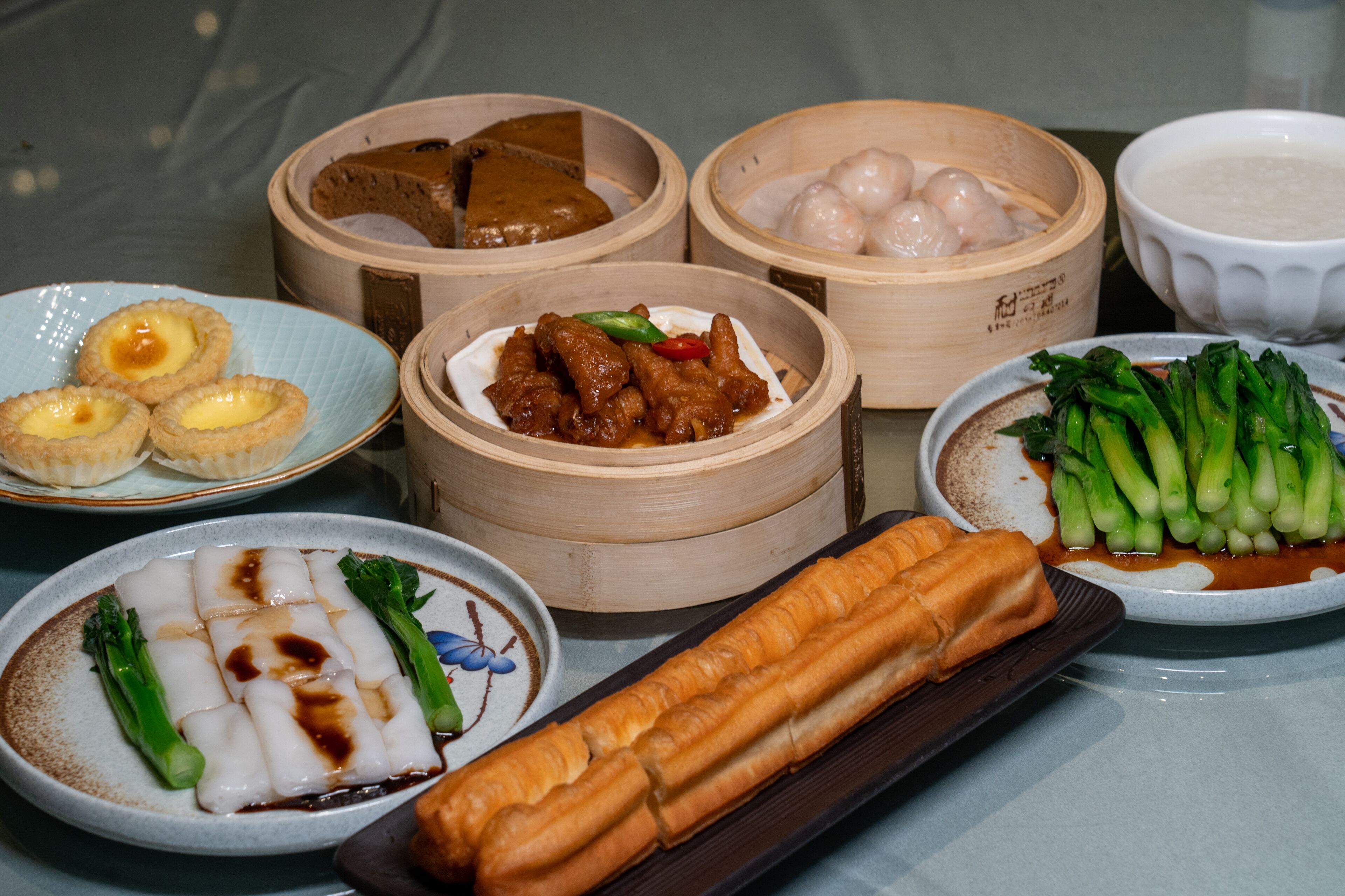 A variety of dishes including dumplings, spring rolls, and a plate with a green vegetable dish.