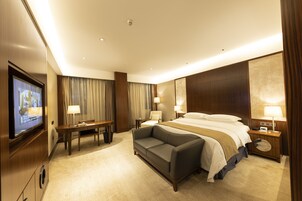 Een hotelkamer met een bed, een slaapbank, een bureau en een televisie.