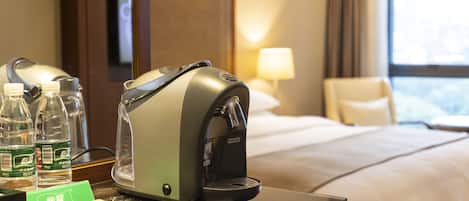 A hotel room with a bed, a coffee machine, and bottled water on the counter.