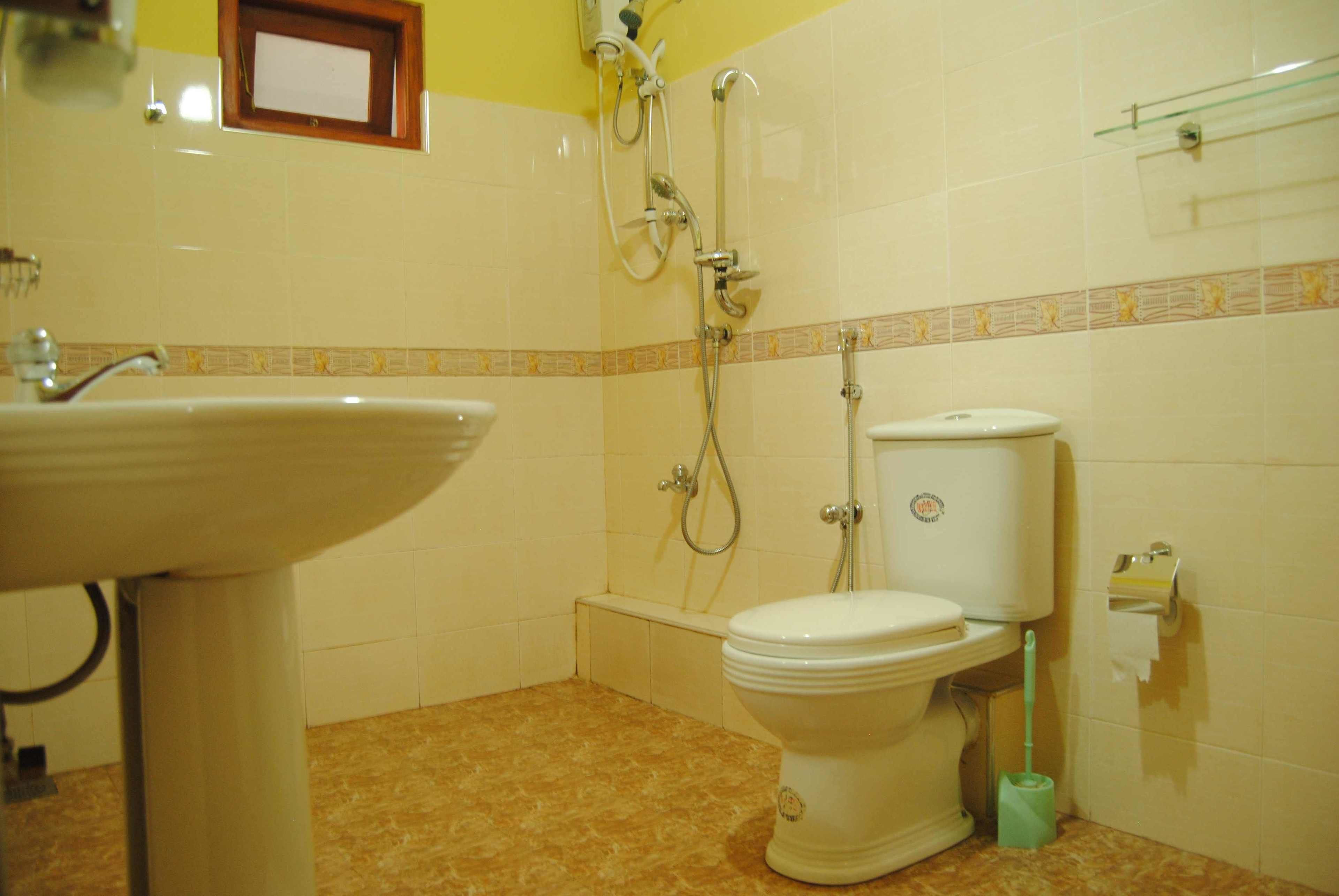 A bathroom with a sink, toilet, shower, and a small window.
