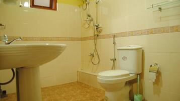 A bathroom with a sink, toilet, shower, and a small window.