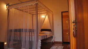 A bedroom with a four-poster bed, a wooden door, and a tiled floor. - Kumara Guesthouse Unawatuna (Unawatuna)